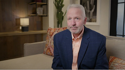A man with grey hair sitting on a sofa