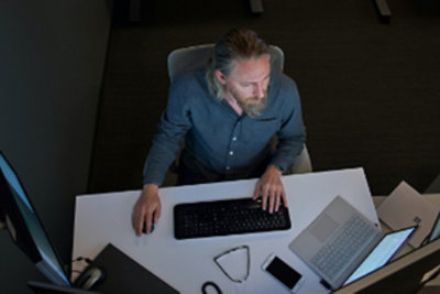 A bird’s eye view of a person working at their desk with multiple screens and a laptop