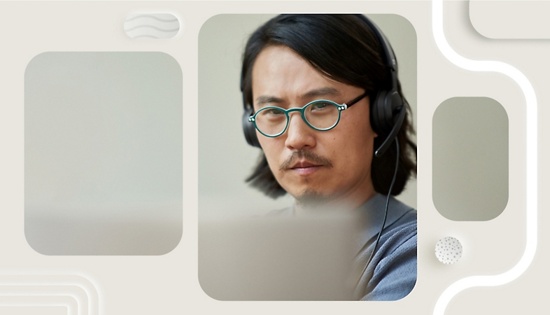 Човек, който носи слушалка над ухото си и използва лаптоп