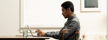 テーブルでノート PC での作業をしている人