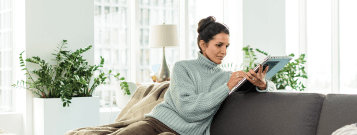 カウチにもたれてタブレットを使っている人