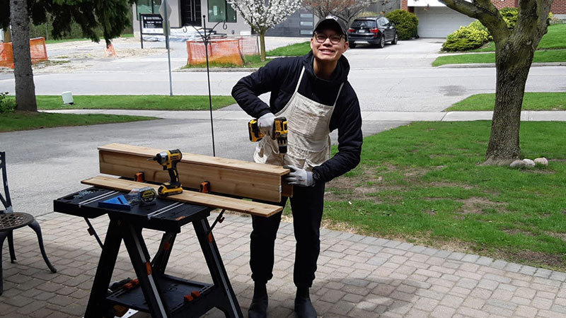 Mitchell Wong is outdoors, woodworking for his business