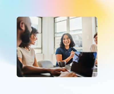 Fire personer sitter rundt et bord i et lyst rom, engasjert i en vennlig samtale.