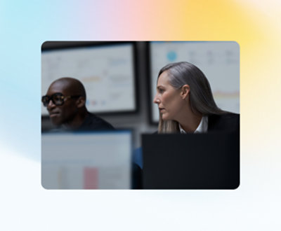 To personer ser på flere skjermer som viser data i et kontormiljø.