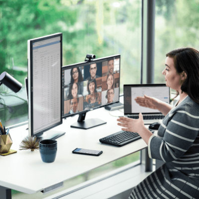 A women explaining using hand gestures over a video call while sitting and multiple screens open on the table