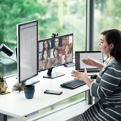 A women explaining using hand gestures over a video call while sitting and multiple screens open on the table