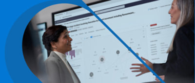 背景顯示在大型電腦螢幕前交談的兩名女性