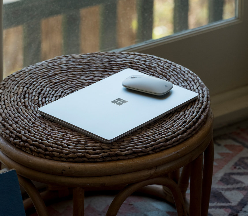 A Surface Laptop Go for Business sits on a table with a Surface Mouse.