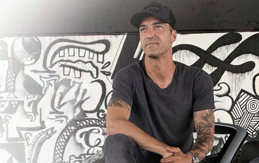 Schriftzug #BleibEcht auf schwarzen Hintergrund und Lucas Luhr der auf einem Auto vor einer Grafitti Wand sitzt und in die Ferne schaut.