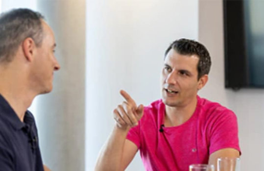 Zwei Männer sitzen sich gegenüber und unterhalten sich.