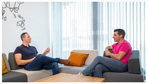 Zwei Männer sitzen sich gegenüber und unterhalten sich.