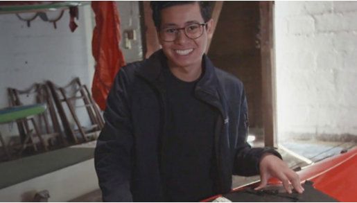 Auftragshacker Philipp Kalweit steht vor einem Kajak und lächelt in die Kamera