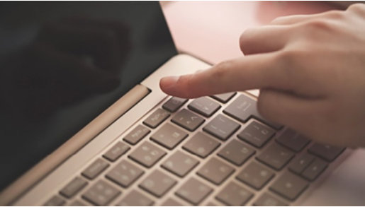 人がノートパソコンのキーボードで入力している