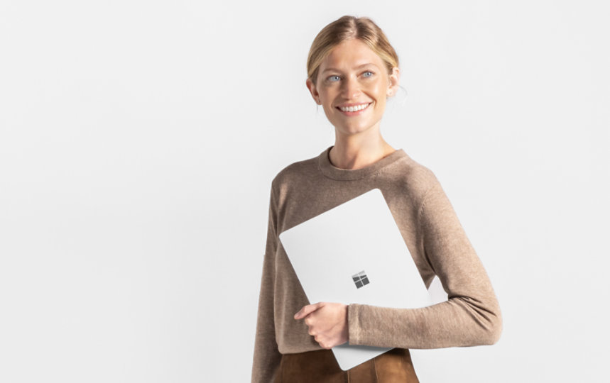 Eine stehende Frau hält einen Windows Surface Pro PC und blickt nach links