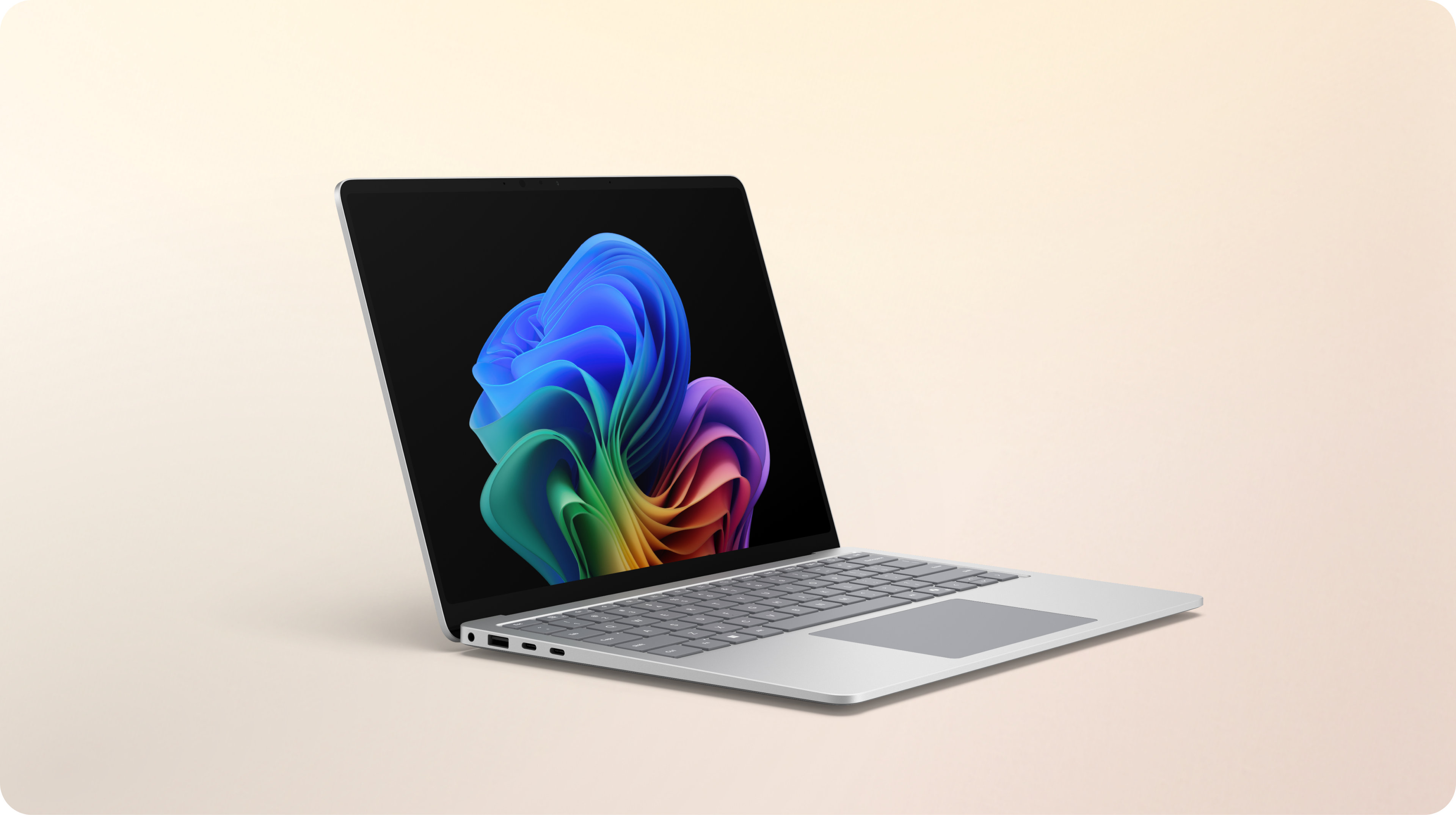 An open built-in AI platinum Surface Laptop facing right displaying the rainbow bloom image against a gradient peach background