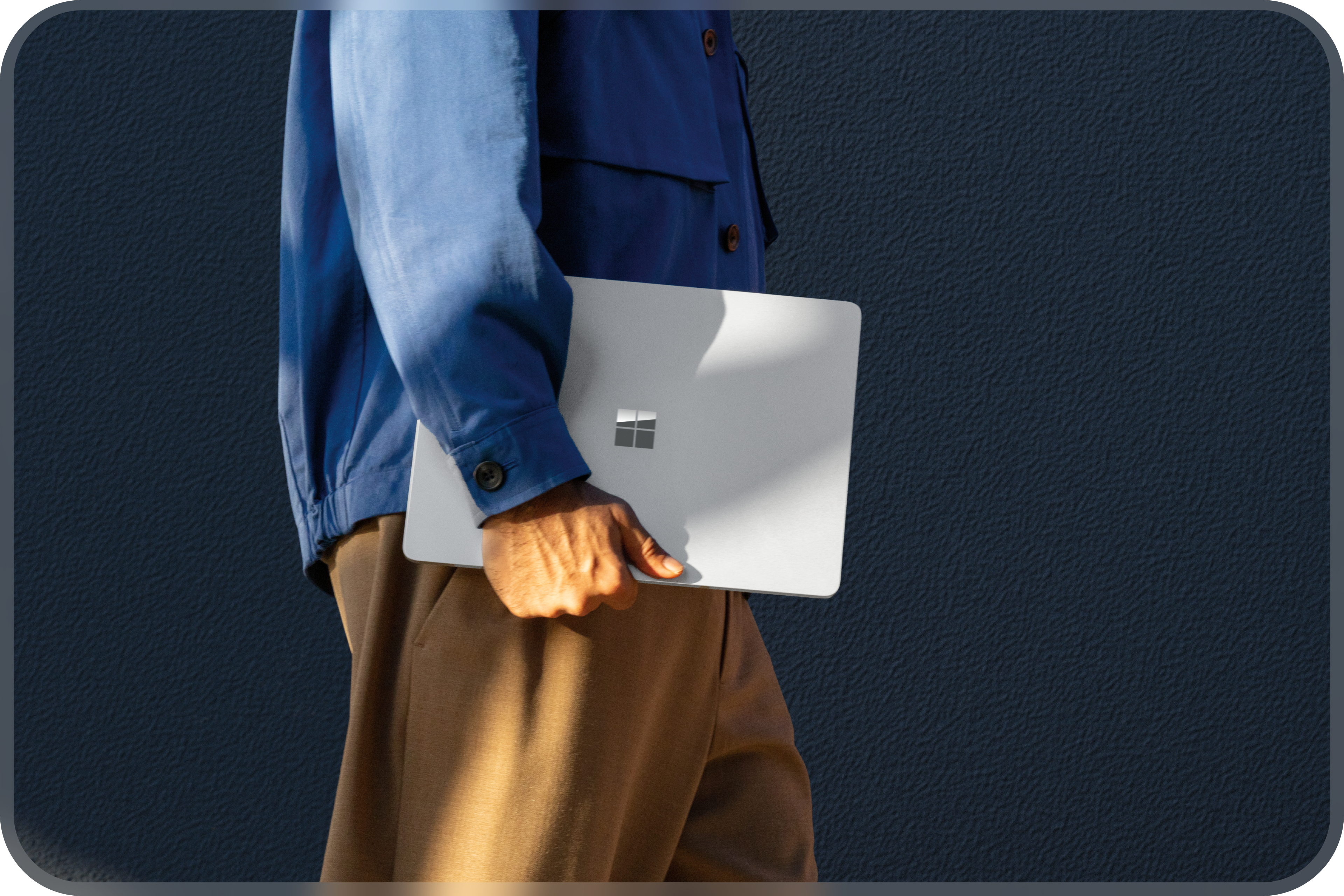 Une personne marche avec un ordinateur portable Windows platine fermé