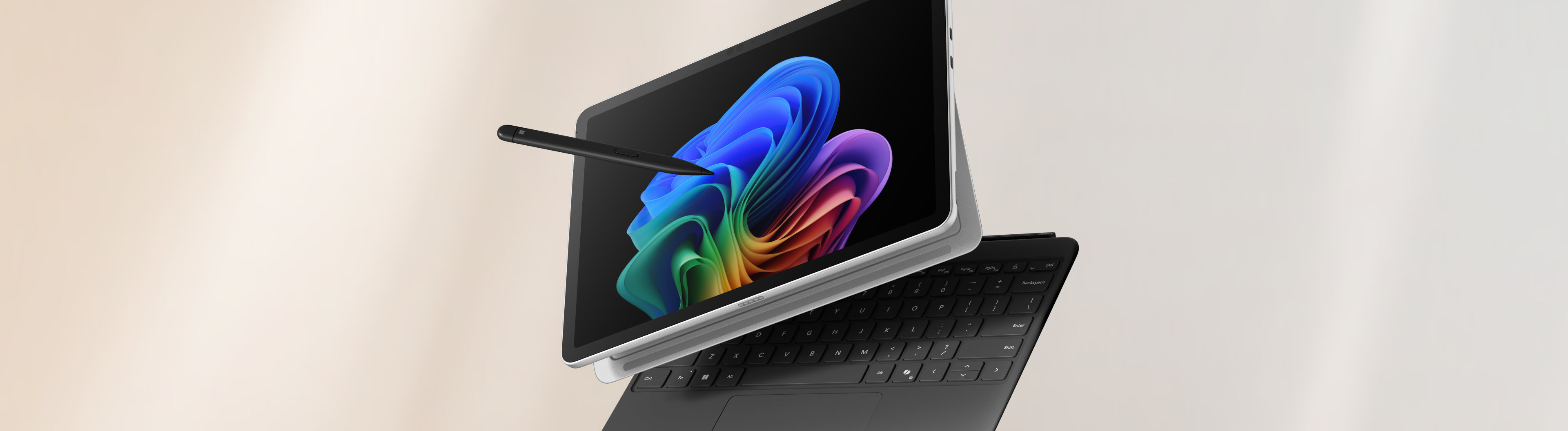 Un PC 2-en-1 ouvert affichant l'image de la fleur arc-en-ciel avec un clavier et un stylet amovibles inclinés de façon spectaculaire sur un fond dégradé pêche et gris