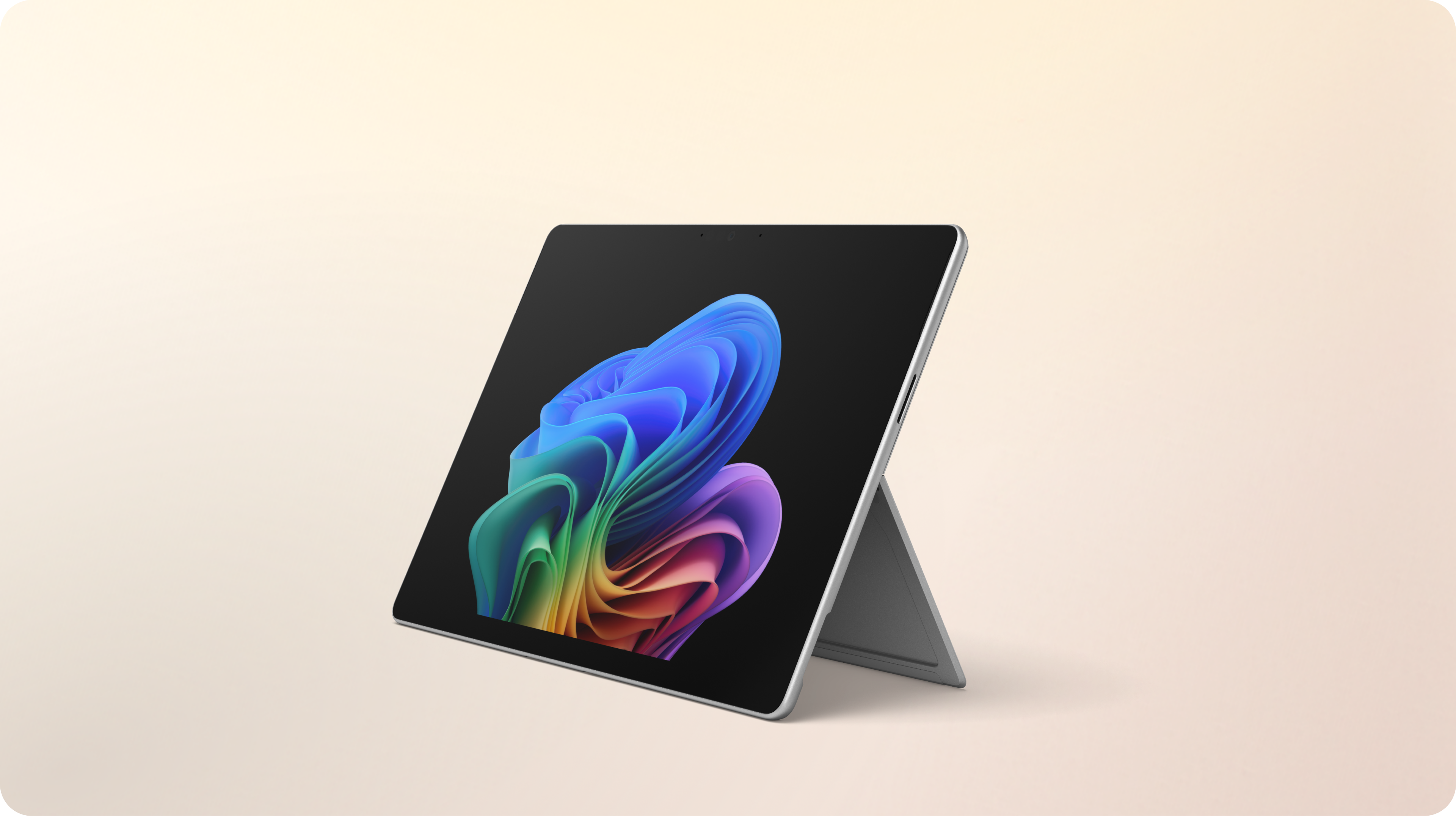 An open Surface Pro 2-in-1 facing left without a keyboard displaying the rainbow bloom image against a gradient peach background