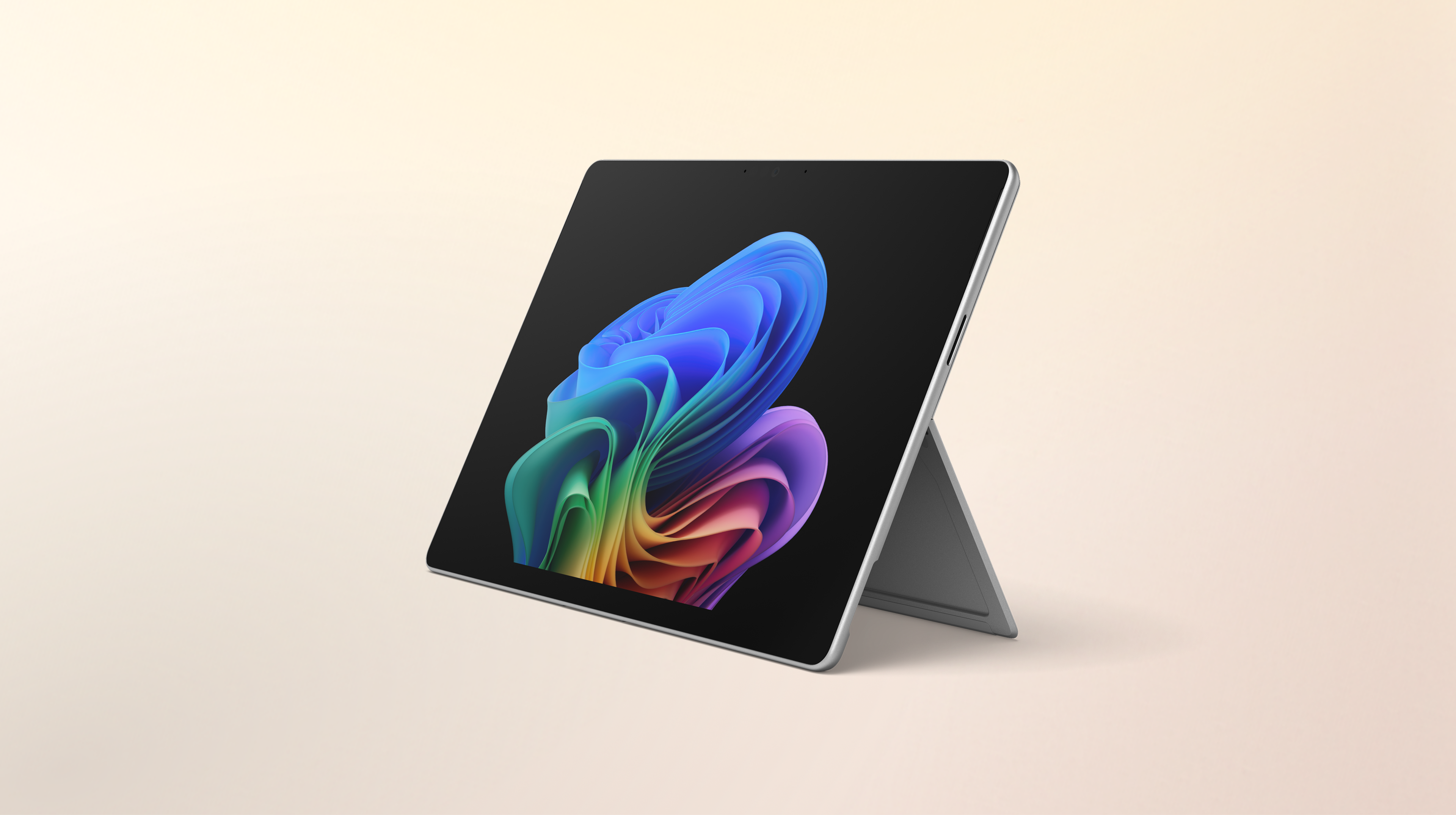 An open Surface Pro 2-in-1 facing left without a keyboard displaying the rainbow bloom image against a gradient peach background