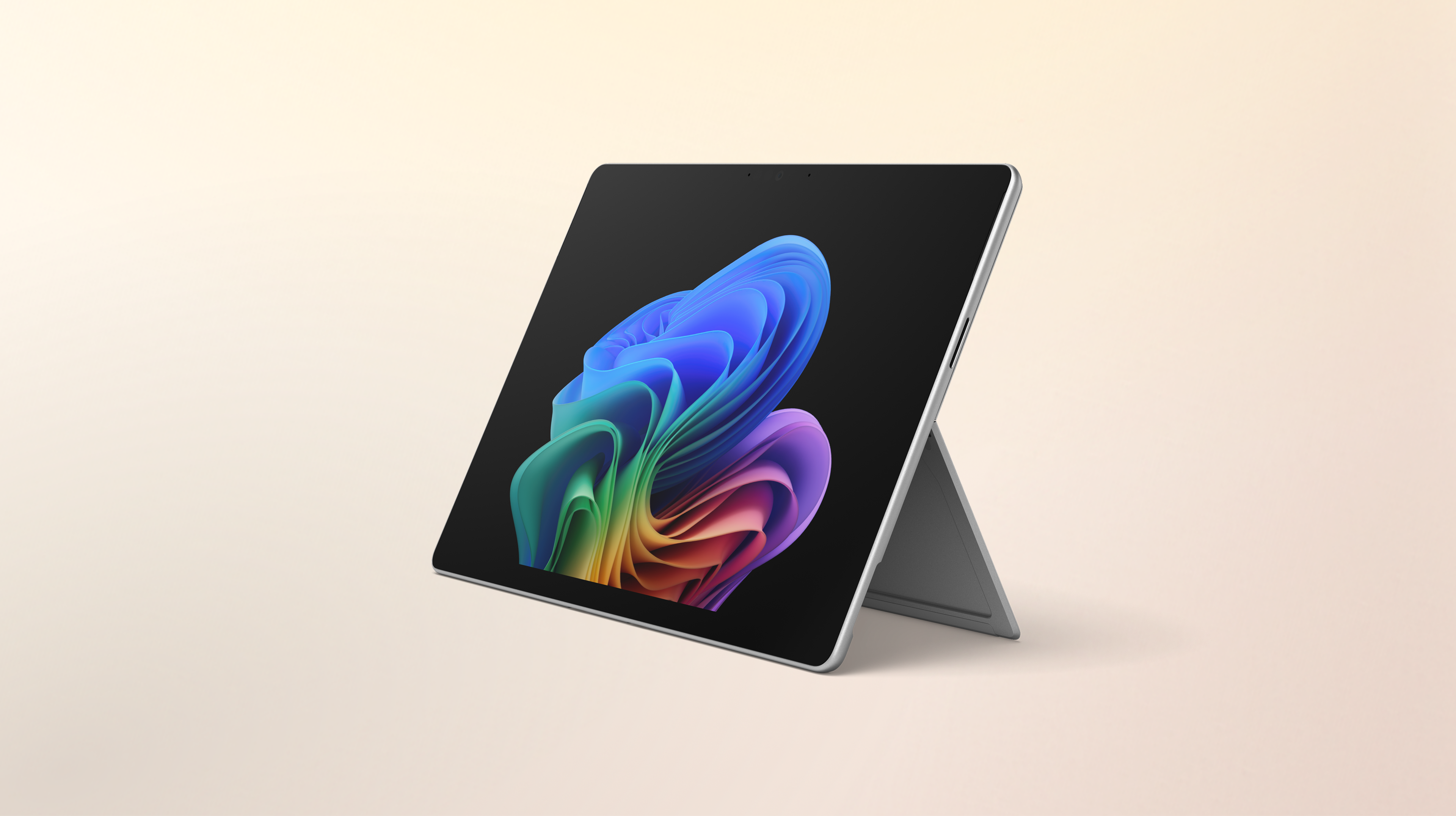 An open Surface Pro 2-in-1 facing left without a keyboard displaying the rainbow bloom image against a gradient peach background