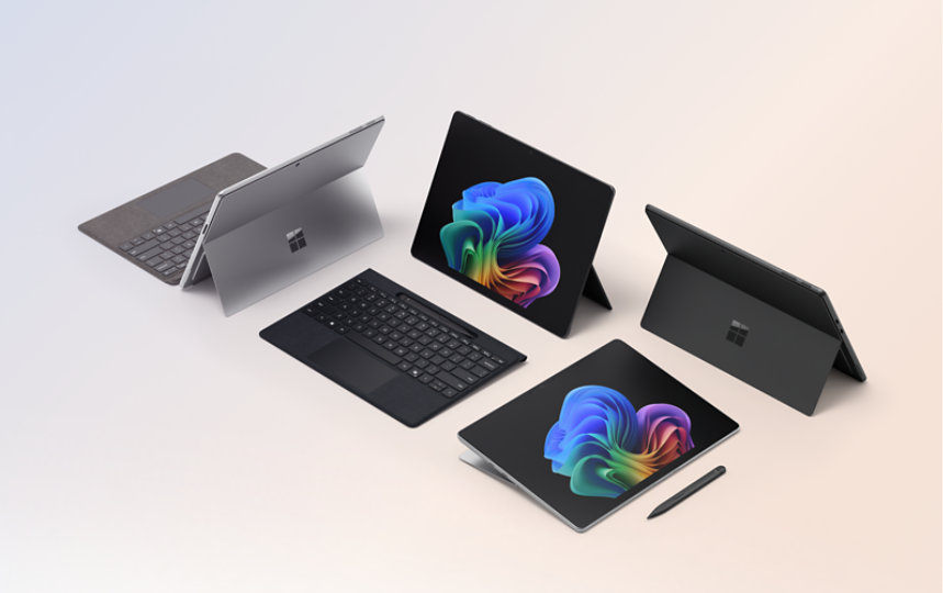 Quatre ordinateurs portables Surface Pro pour les entreprises, dont deux affichent l'image de la fleur arc-en-ciel, l'un avec un clavier détachable, l'autre avec un stylet, sur un fond bleu et pêche dégradé.