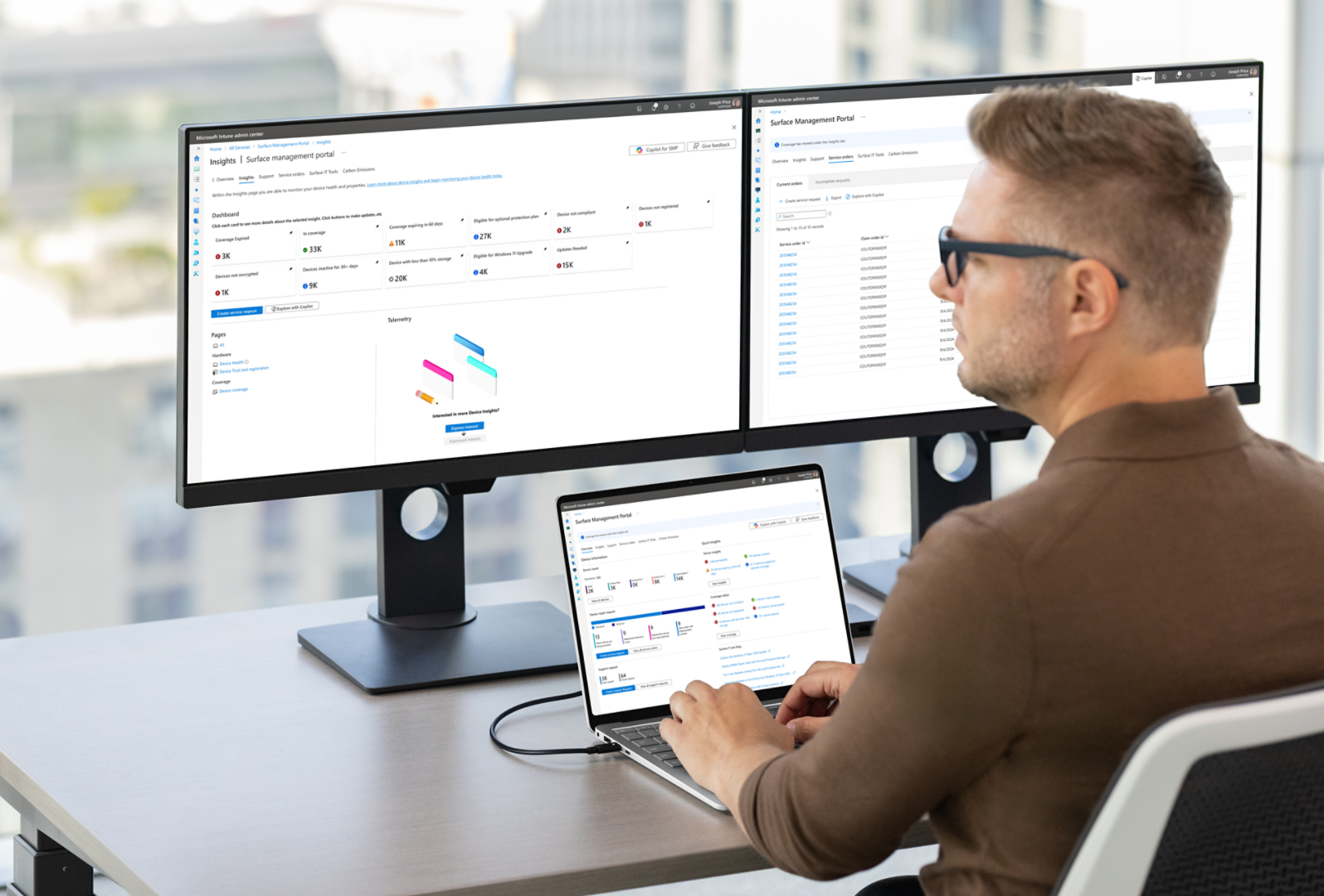 Office worker with a Windows Surface device displaying workflow insights and two external monitors on a desk in front of a large window with cityscape