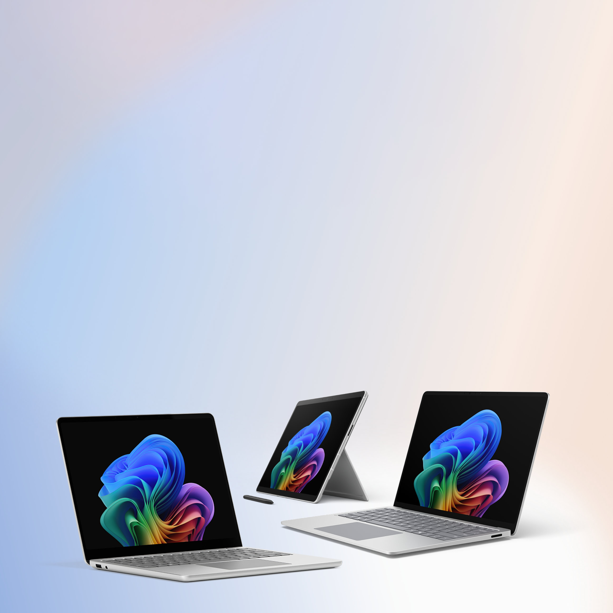Three open Surface for Business devices, two Laptops with keyboards, one 2-in-1 device with a stylus and without a keyboard, all displaying the rainbow bloom image.