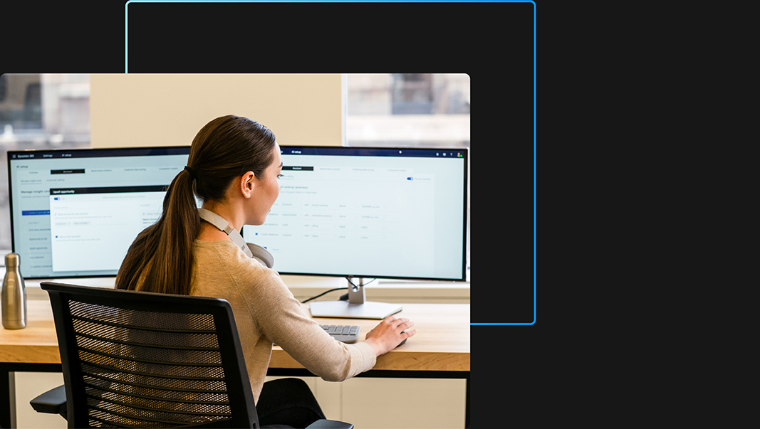 Vrouw aan het werk in kantoor met twee monitors, met koptelefoon om haar nek en bezig met een muis.