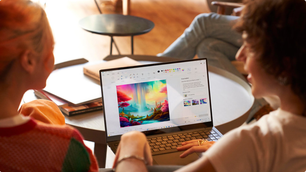 Divi cilvēki sēž pie klēpjdatora ar atvērtu programmu Molberts