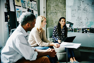 שלושה אנשים יושבים ומנהלים דיון בסביבה משרדית. 