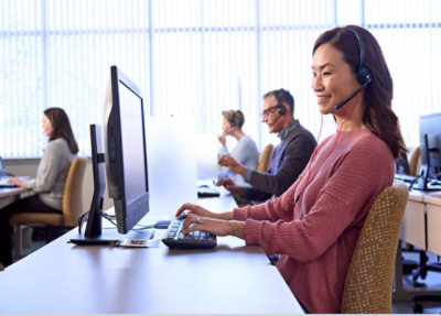 A woman wearing a headset and typing on a keyboard.