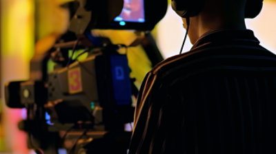 Person working on video editing software with colorful timelines and audio levels visible on the monitor.
