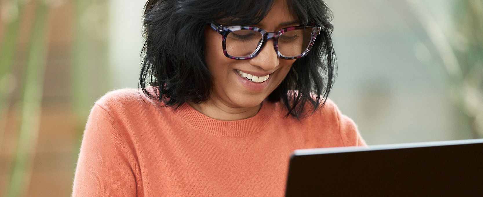 A person smiling and typing on a laptop
