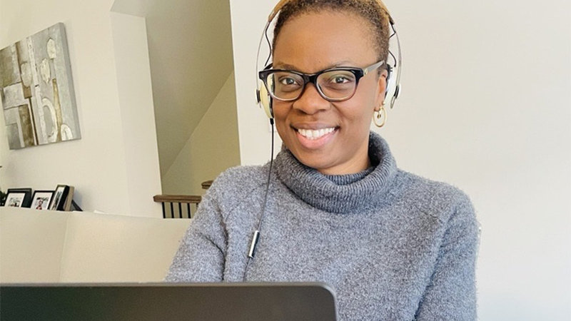 Nike Adediwura smiling while working on her Microsoft Surface from her home office. 