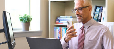 A man wearing glasses holding a phone.