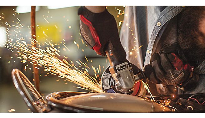 A person using a grinding wheel on a piece of metal.