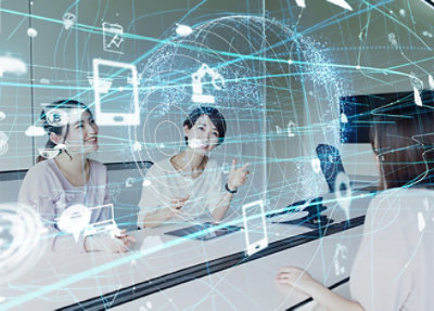 Three people in a meeting room, smiling and discussing, with digital graphics of technology icons and a network globe overlaying the image.