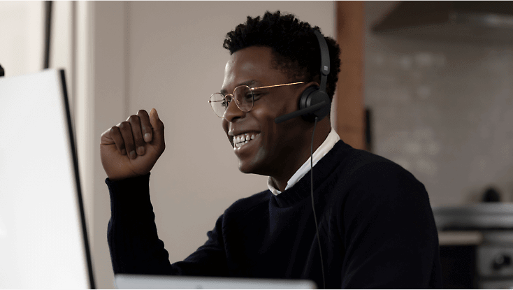 Una persona con unos auriculares sonriendo y trabajando en su escritorio.