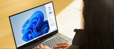 Person using a laptop with a blue abstract wallpaper on the screen.