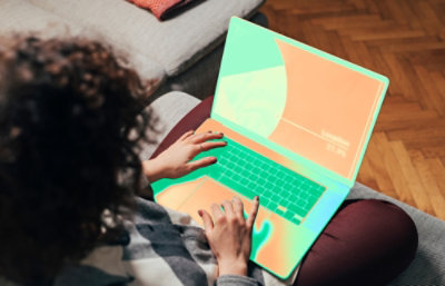 Henkilö istuu sohvalla käyttäen kannettavaa tietokonetta.