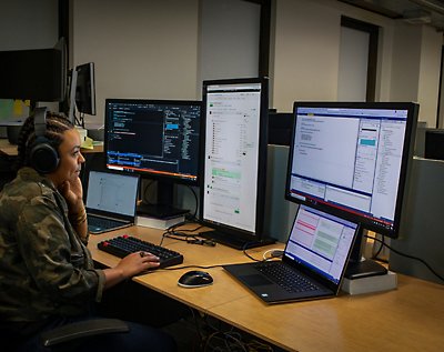 Eine Frau sitzt an einem Schreibtisch mit zwei Monitoren vor sich