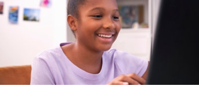 Person in a purple shirt sitting on a couch with a laptop, engaged in a conversation or activity.