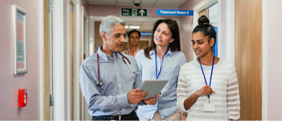 A group of people in a hallway looking at a tablet.