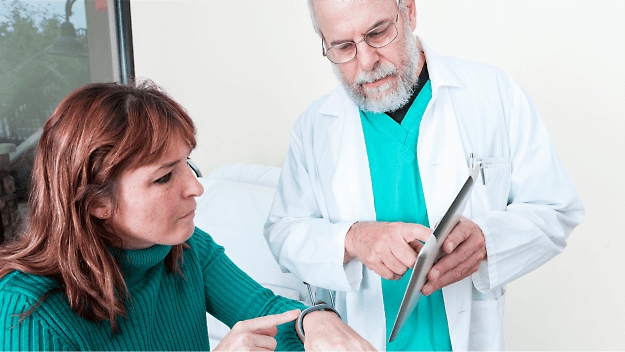 Eine medizinische Fachkraft zeigt einem Patienten Informationen auf einem Tablet