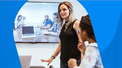 Two people in a meeting room on a video call with another team being displayed on a large screen on the wall.