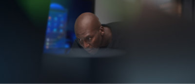 서서 컴퓨터를 들여다보는 사람