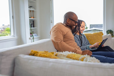 Dvije osobe sjede na kauču i gledaju u računalo