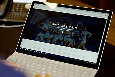 膝上型電腦，上面有顯示著 QNET AND SPORTS 的網頁