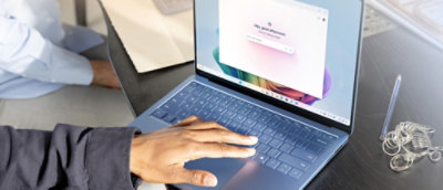 A person typing on a laptop with a computer screen showing a login page.