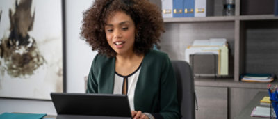 A woman sitting in a chair looking at a laptop.
